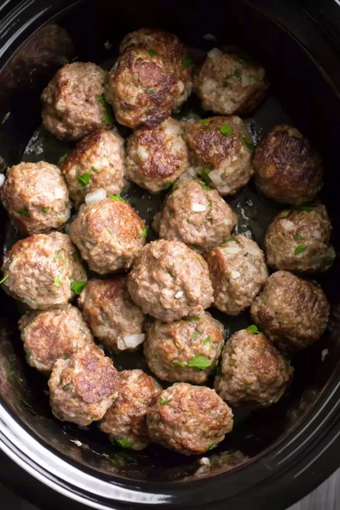 Seared Italian meatballs in a crockpot before adding marinara sauce