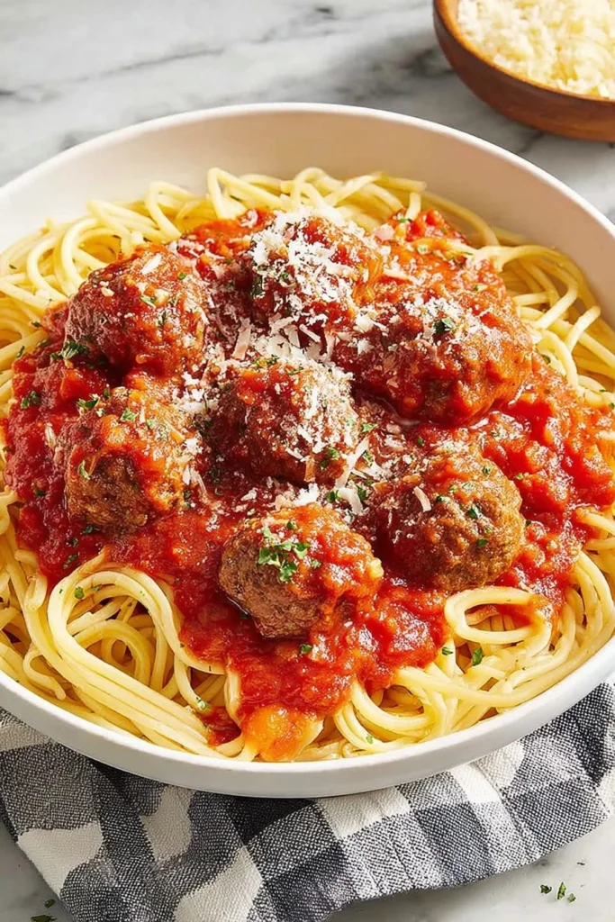 Italian meatballs in tomato sauce served over spaghetti and topped with grated parmesan