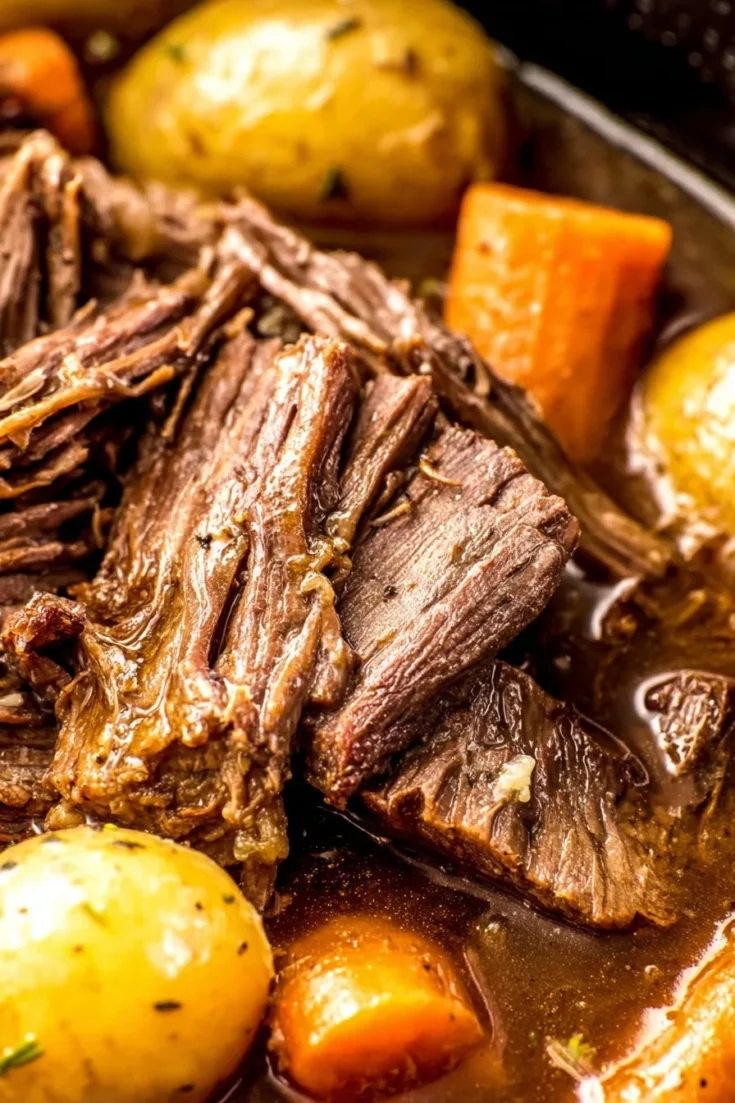 Close-up of juicy shredded crockpot rump roast with baby potatoes and carrots in thick brown gravy